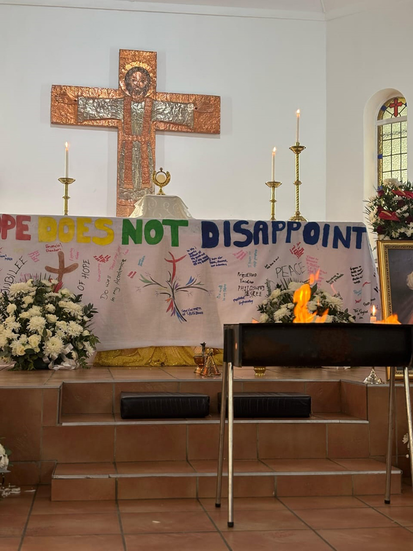 A church altar during Adoration, with a banner displaying the hopes and dreams of youth.