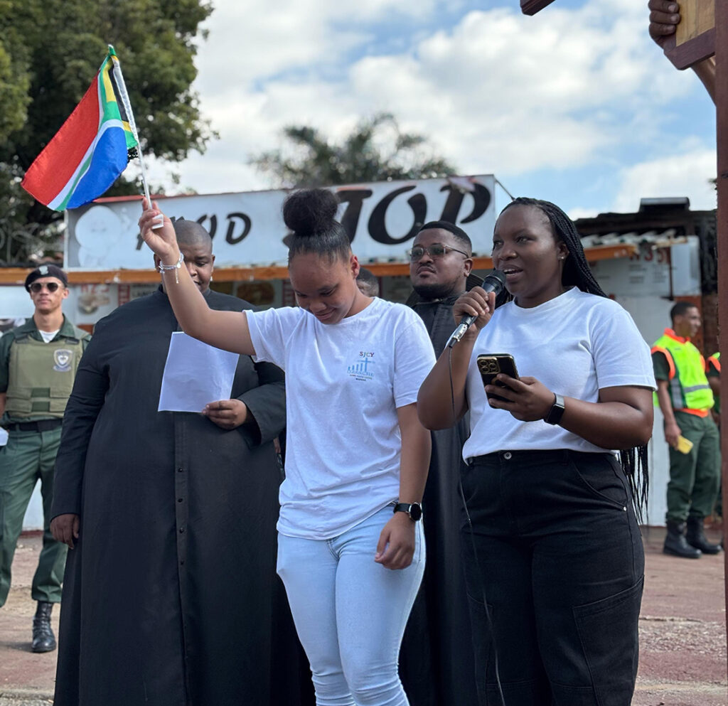 Youth praying during a procession, highlighting national and personal challenges.