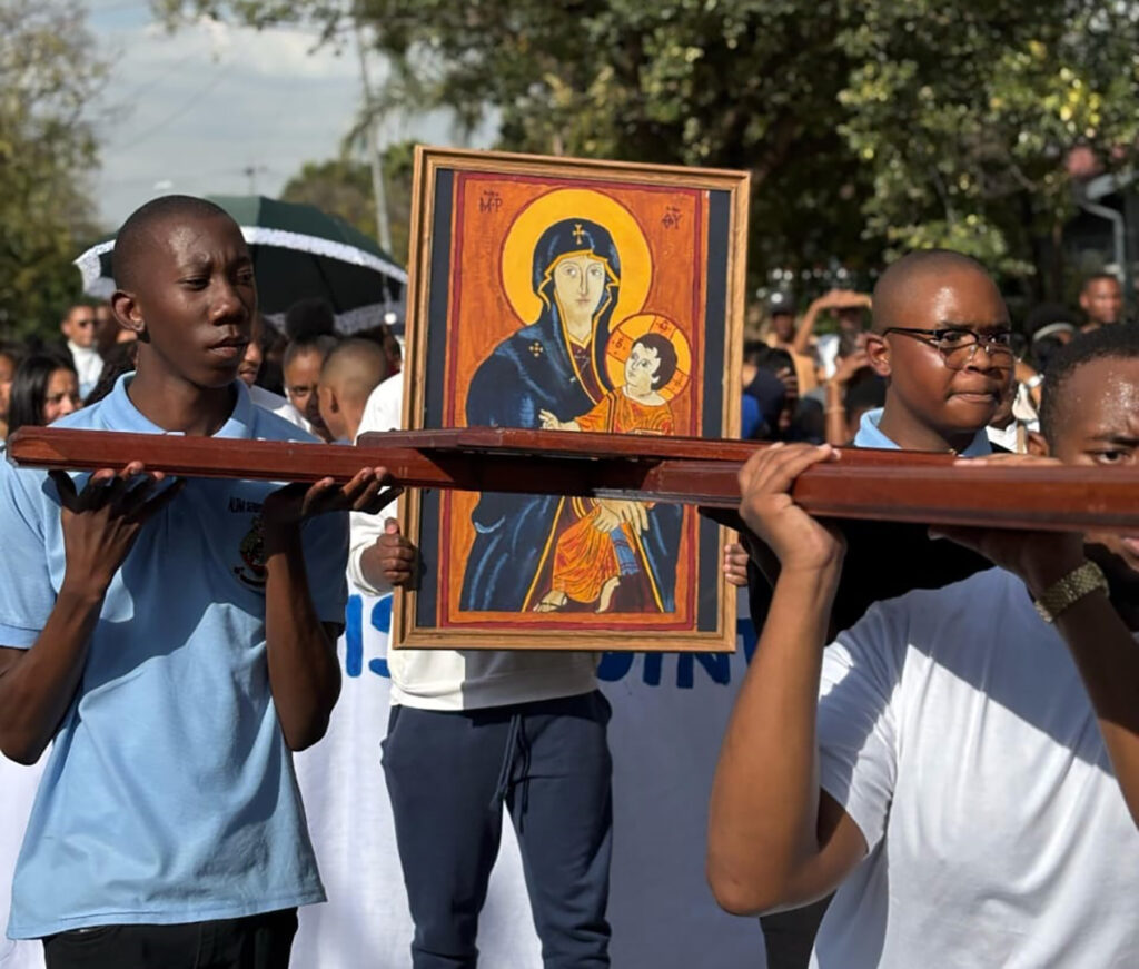 Young people carrying the Cross and a portrait of Our Lady of Good Hope in a procession.